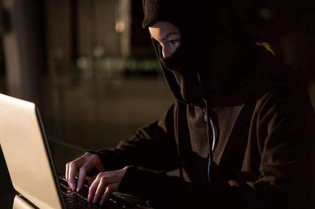 Woman in balaclava using laptop in the office.jpeg