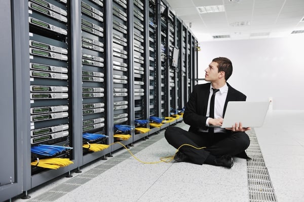 young engeneer business man with thin modern aluminium laptop in network server room